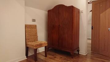 Ein Zimmer mit einem Holzschrank, einem Korbstuhl und einer Holztür.