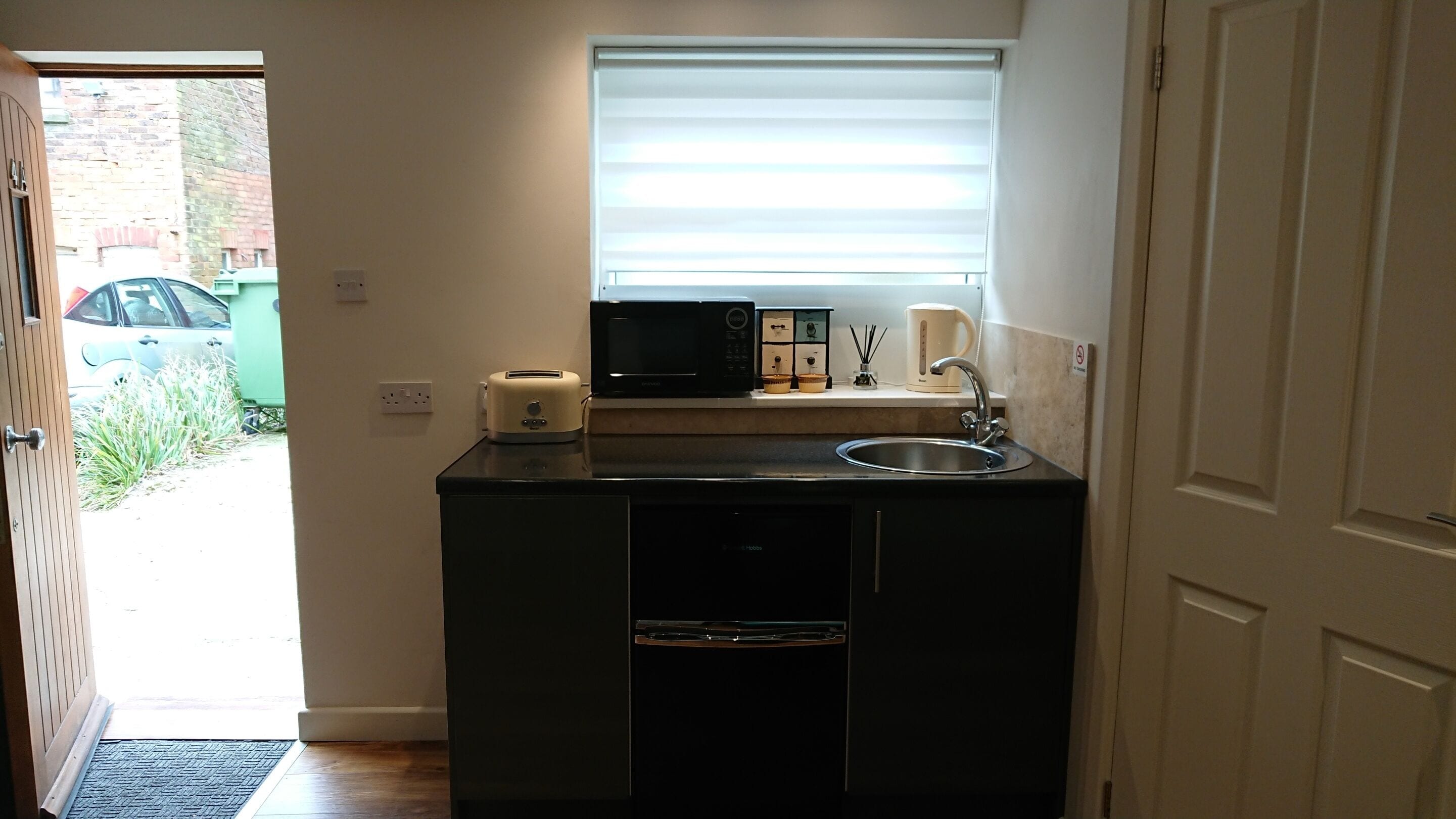 A compact kitchen with a microwave, toaster, and sink.