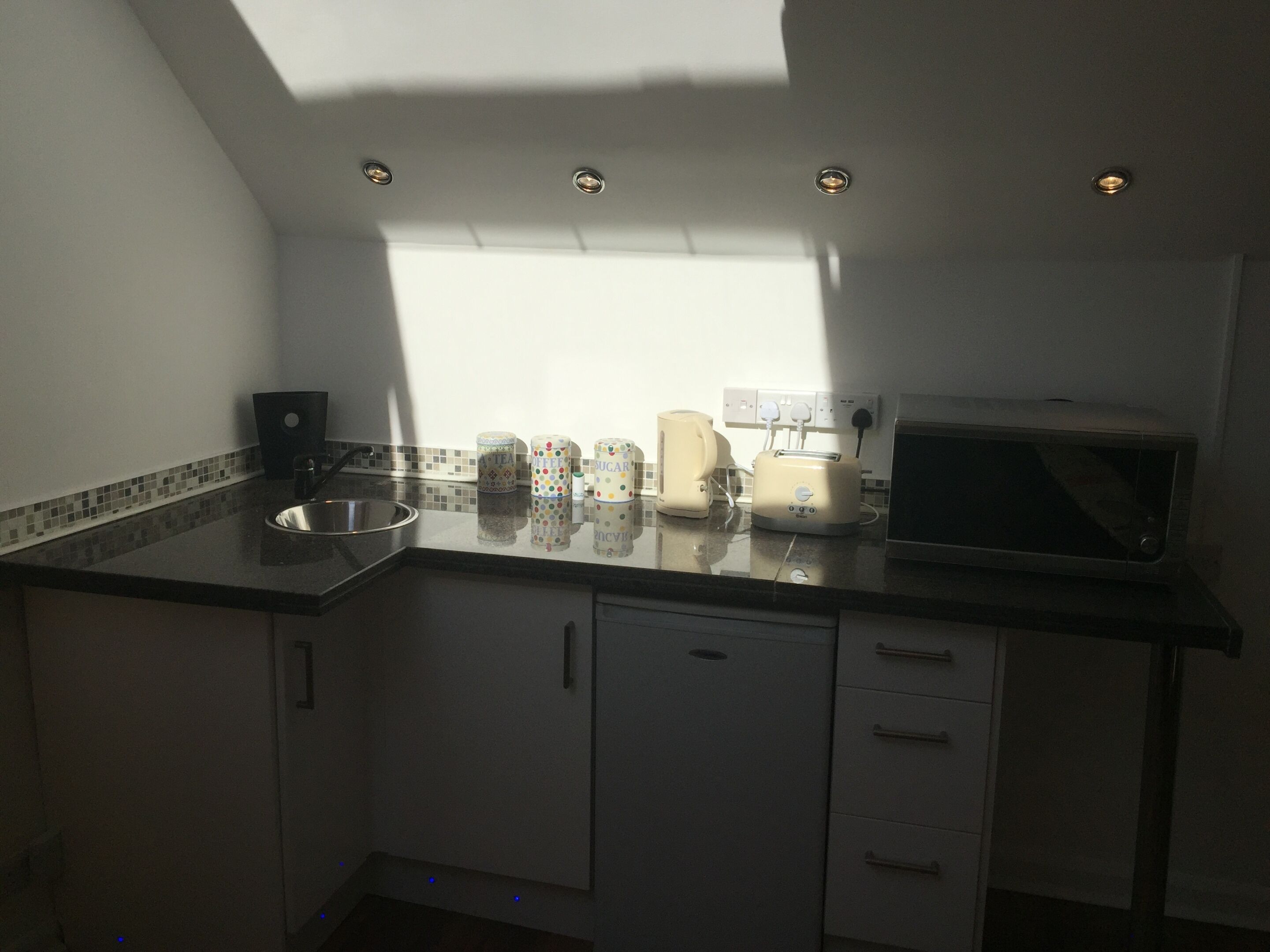 Een keuken met een raam, een broodrooster, een waterkoker en een magnetron.