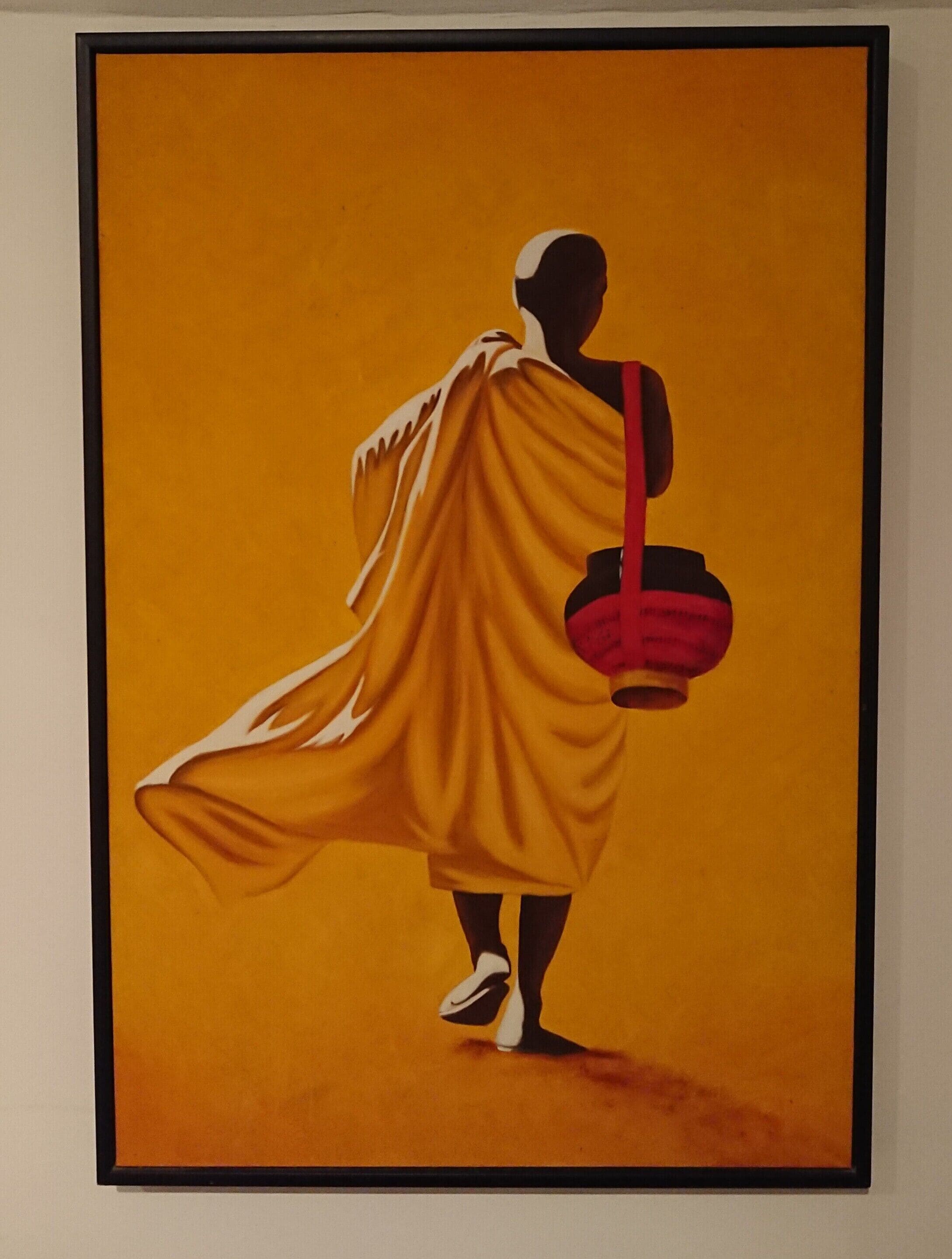 A framed artwork of a figure in a flowing yellow garment holding a red object.