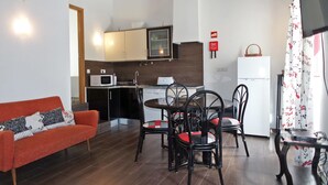 Un espace de vie compact comprenant un coin cuisine, un coin repas avec une table et des chaises, et un canapé.
