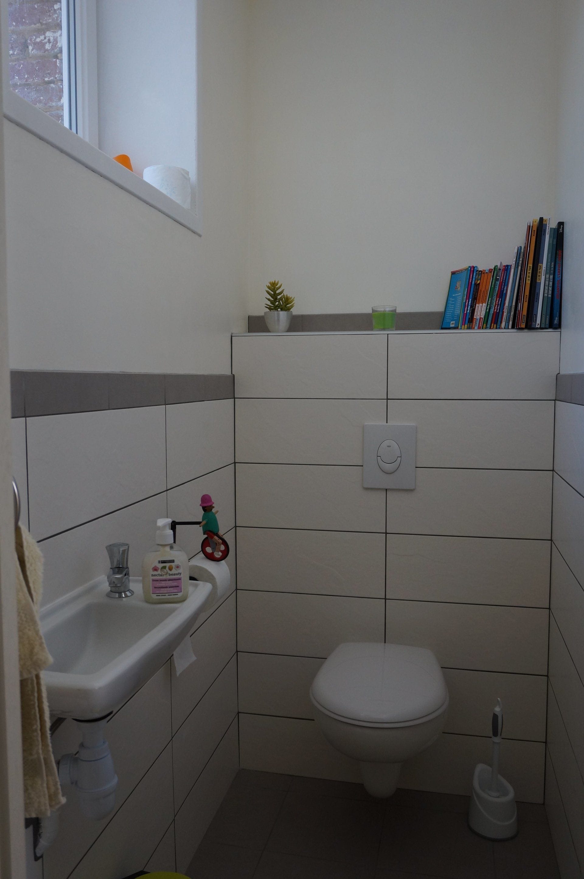 Une petite salle de bain propre, équipée de toilettes, d’un lavabo et d’une fenêtre.