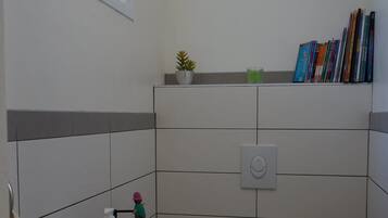 Une petite salle de bain propre, équipée de toilettes, d’un lavabo et d’une fenêtre.