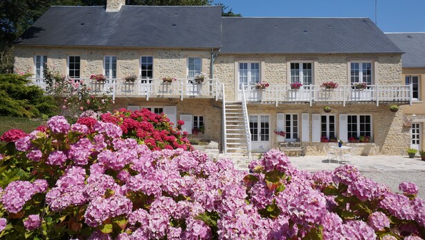 A stone building with multiple balconies, a staircase, and outdoor seating. - B&B Le Clos Saint-Jean - Omaha Beach (Aure sur Mer)