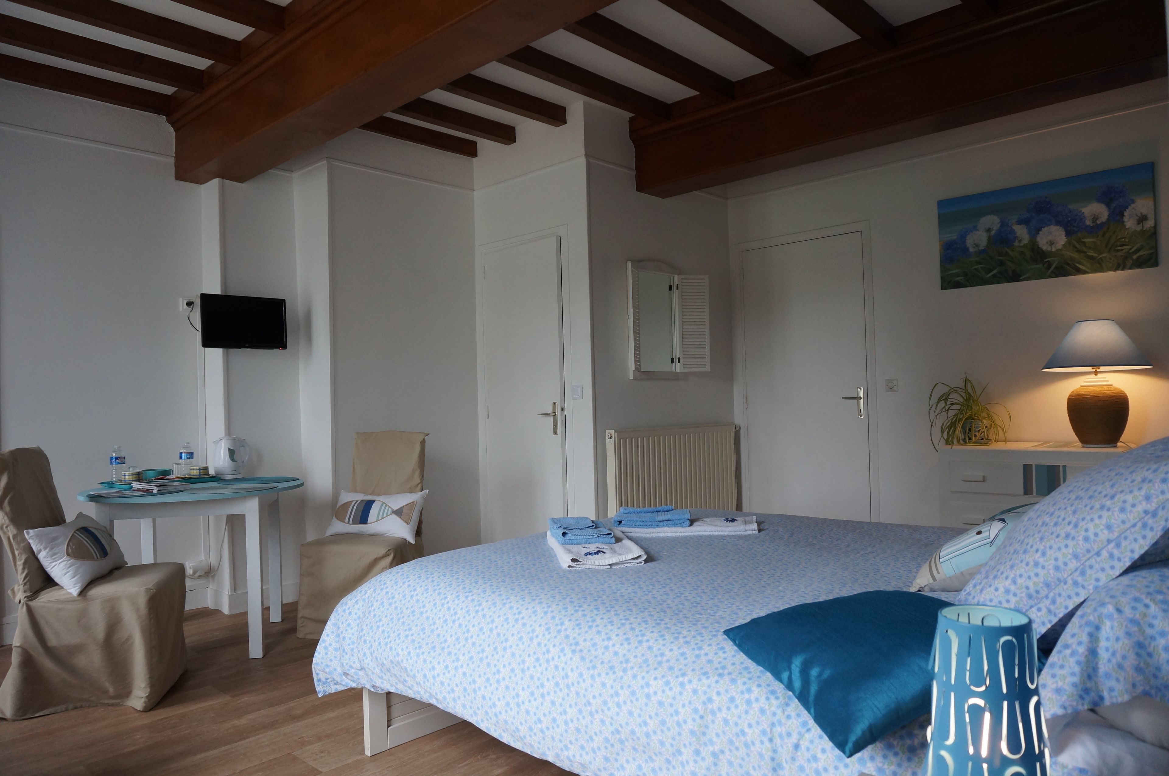 Une chambre à coucher comprenant un lit, un bureau, une chaise, un téléviseur, un radiateur et un tableau.