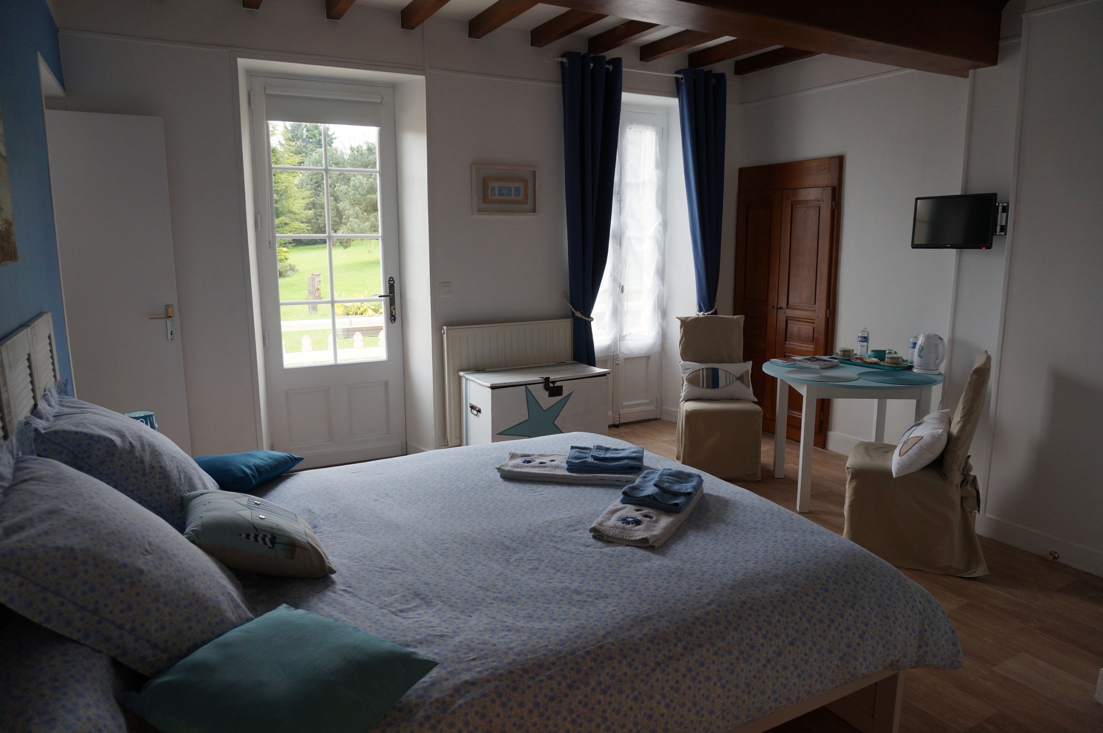 Un dormitorio con cama, escritorio, silla, televisor y ventana con cortinas.