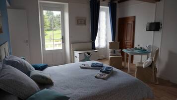 Un dormitorio con cama, escritorio, silla, televisor y ventana con cortinas.