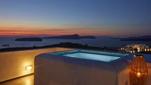 Une piscine sur le toit, offrant une vue sur la mer et les îles au coucher du soleil.