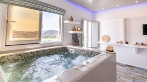 Une salle de bain moderne avec une grande baignoire, une fenêtre donnant sur l’extérieur et une étagère contenant des articles de toilette.