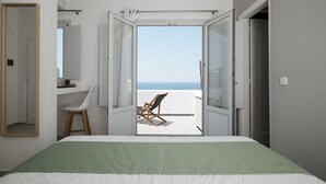 Une chambre à coucher avec un lit, une chaise et une vue sur la plage, visible par une porte ouverte.