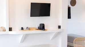 Une salle de bain moderne avec une baignoire, un téléviseur fixé au mur et une étagère contenant des articles de toilette.