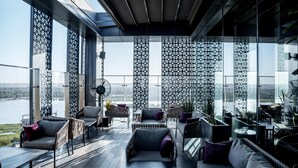 A modern indoor space with large windows, a view of a body of water, and a seating area with chairs and a table. - Radisson Blu Hotel & Conference Center, Niamey (Niamey)