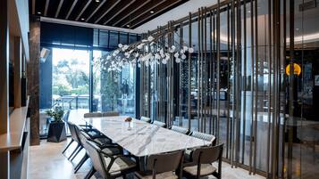 A modern dining area with a marble table, cushioned chairs, and a unique hanging light fixture.