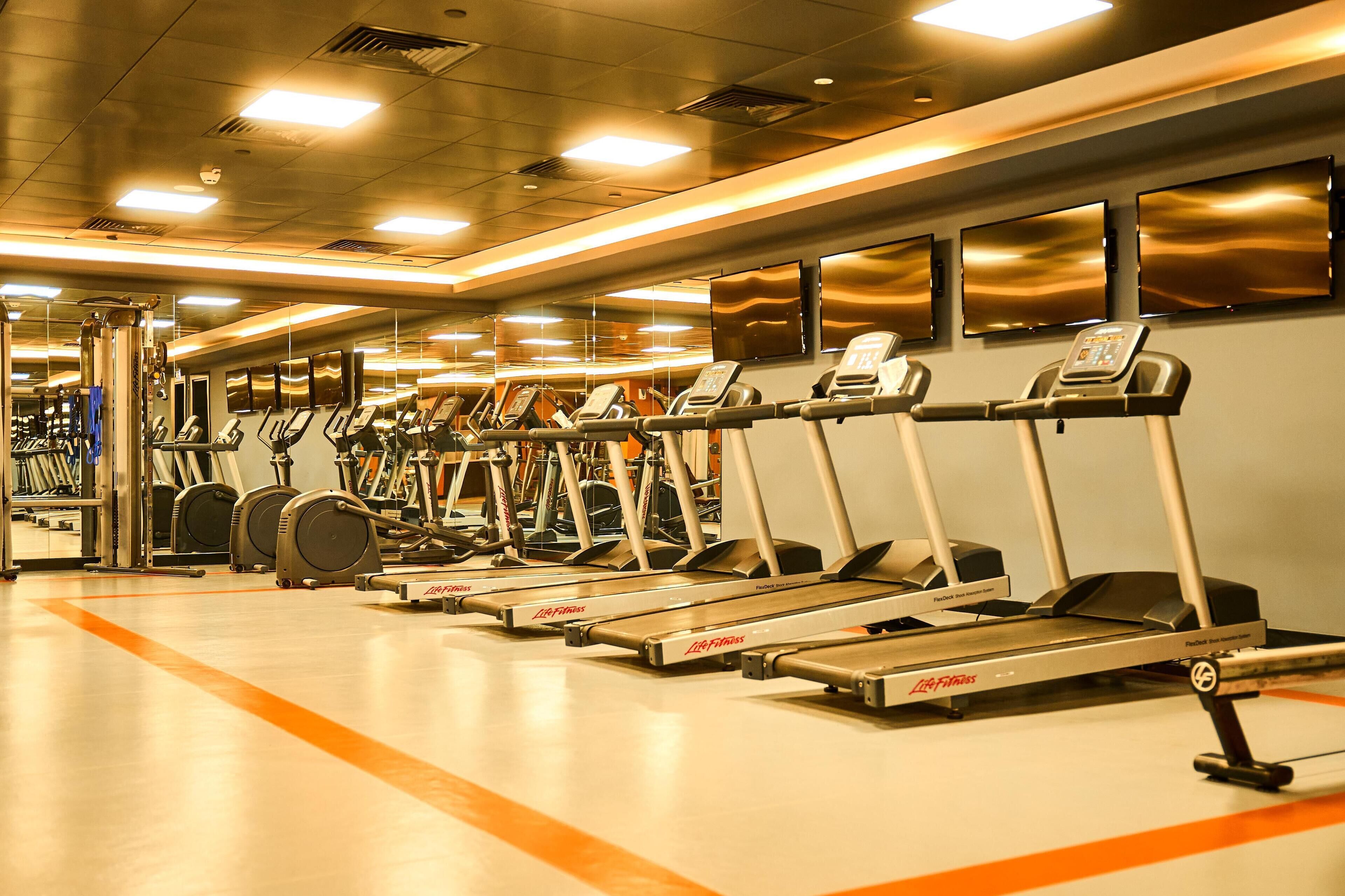 Ein Fitnessstudio mit mehreren Laufbändern und Trainingsgeräten.