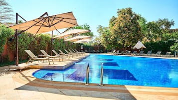Alberca al aire libre, sombrillas en la alberca y camastros
