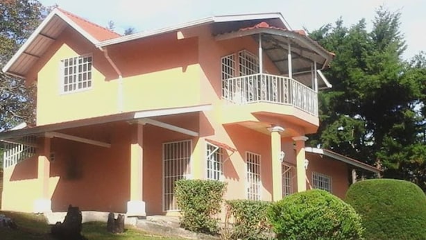 A two-story house with a balcony, a covered porch, and a well-maintained lawn. - Cabaña el Paisaje (Boquete)