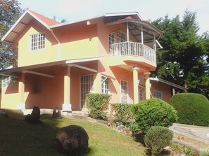 A two-story house with a balcony, a covered porch, and a well-maintained lawn. - Cabaña el Paisaje (Boquete)