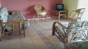A living room with a sofa, two chairs, a television, and a painting on the wall. - Cabaña el Paisaje (Boquete)