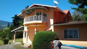 A two-story house with a balcony, satellite dish, and a well-maintained lawn. - Cabaña el Paisaje (Boquete)