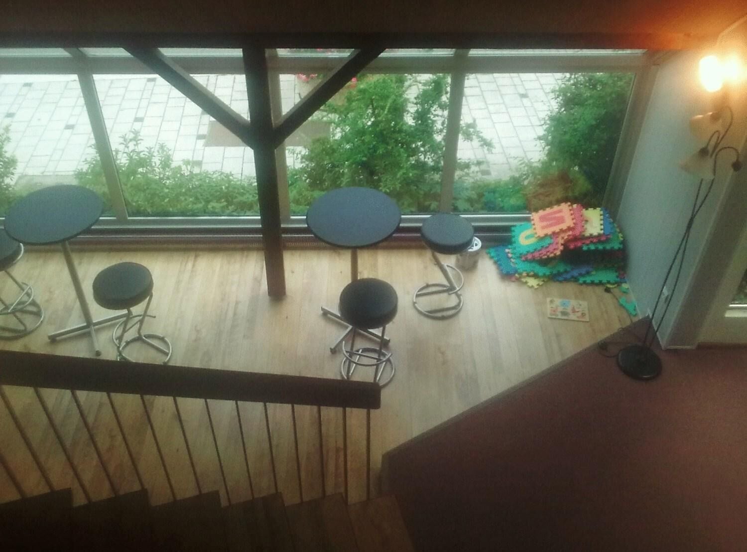 Une terrasse en bois avec quatre tables rondes et un tapis de jeu coloré.