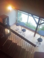 Una habitación con una escalera de madera, un televisor y tres mesas redondas.