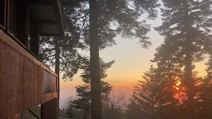 A wooden cabin with a balcony overlooking a forested area during sunset. - The Fireside Inn (Idyllwild)
