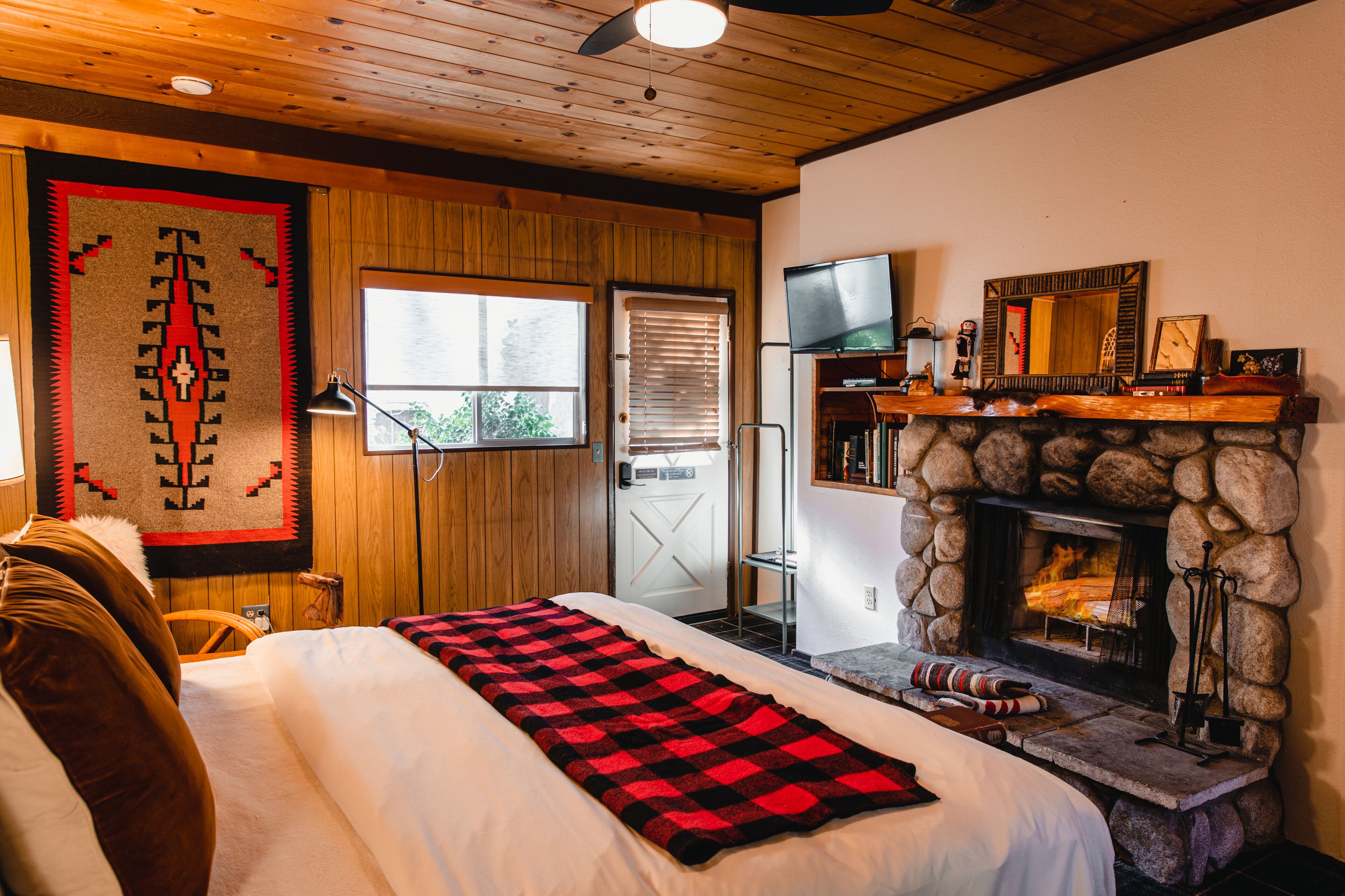 Een knus verblijf met een bed, een open haard, een televisie en een houten plafond.
