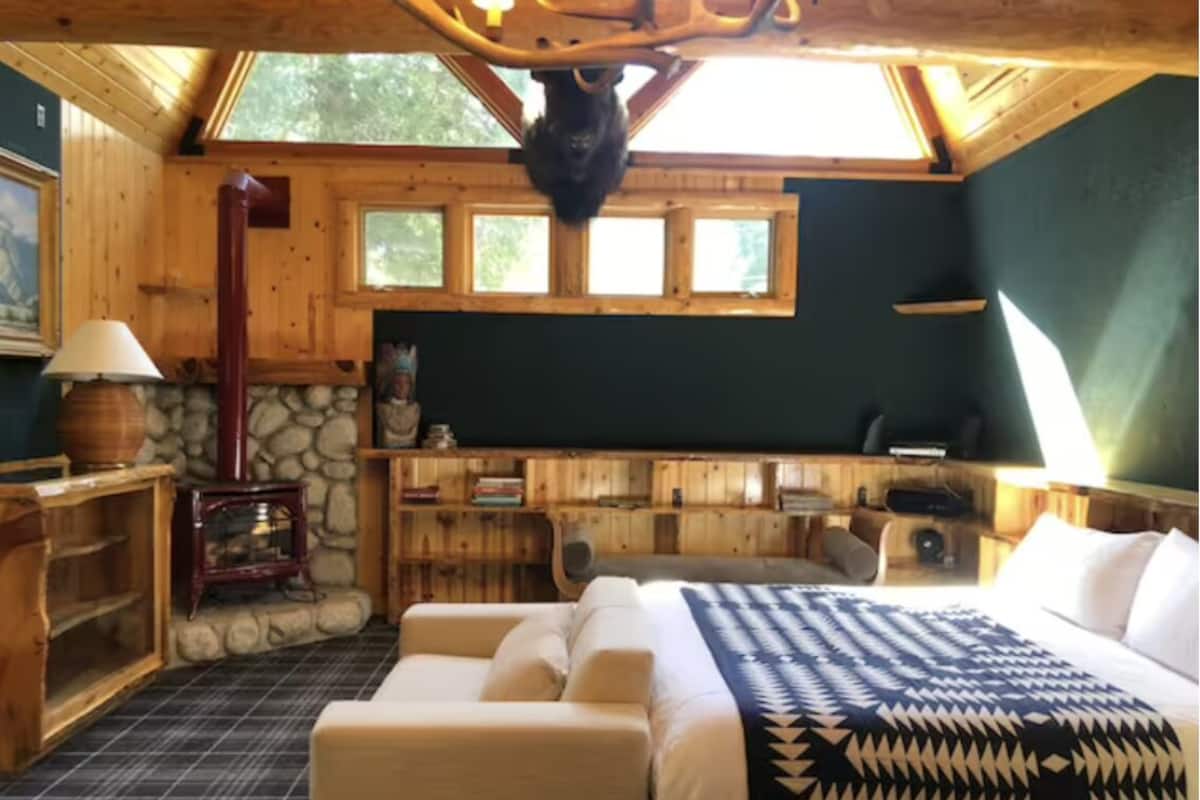 A cozy room with a bed, a fireplace, and a stone wall.