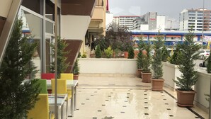A rooftop terrace with potted plants, outdoor seating, and a view of the surrounding buildings. - Ankara Atlantik Otel (Ankara)