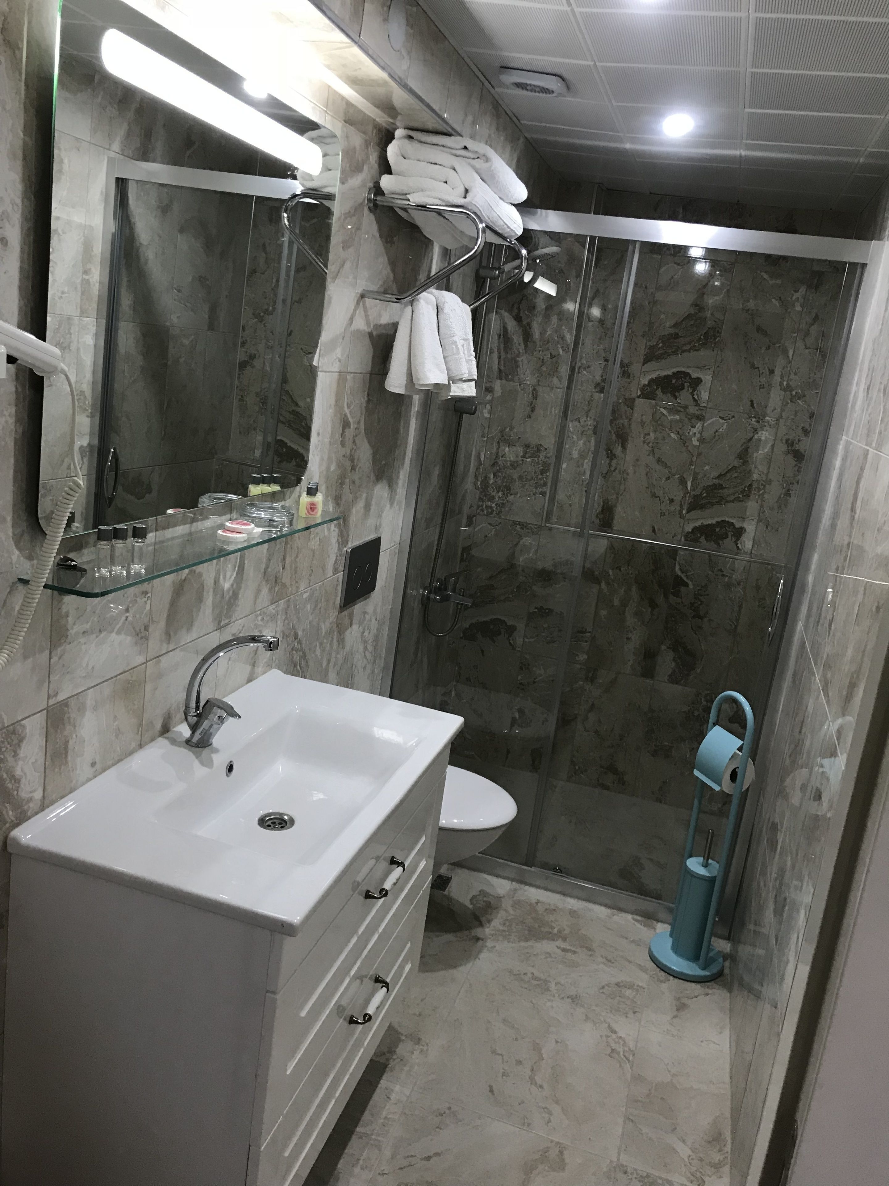 A bathroom with a white sink, mirror, and towel rack.
