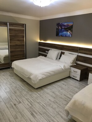 A modern bedroom with a large bed, a nightstand, a bedside table, a wardrobe, and a wall-mounted picture. - Ankara Atlantik Otel (Ankara)