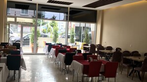 A restaurant with tables and chairs arranged in rows, large windows, and a view of the street outside. - Ankara Atlantik Otel (Ankara)