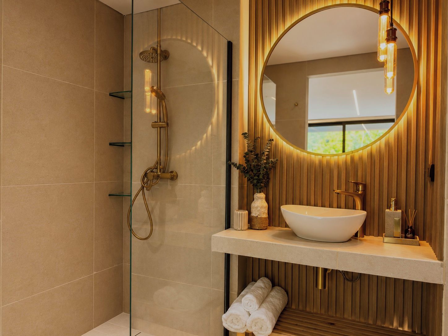 Une salle de bain moderne avec une douche à parois de verre, un grand miroir ovale et un meuble-lavabo en bois.