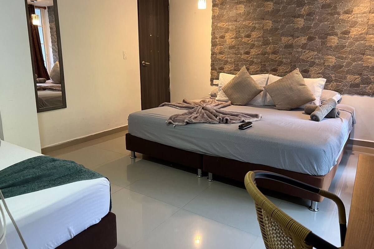 Une chambre à coucher avec un lit, une chaise et un mur en pierre.