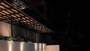 Une piscine au design moderne, entourée d’un mur en béton et agrémentée d’une structure en forme de pergola.