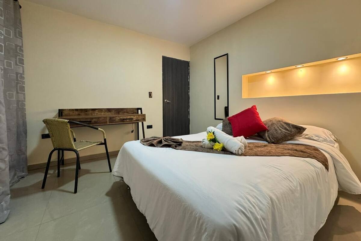 Une chambre d’hôtel avec un lit, un bureau, une chaise et une porte.