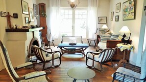 Un salon chaleureux avec une cheminée, des meubles en bois et des œuvres d’art accrochées aux murs.