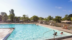 A swimming pool with clear blue water, surrounded by lounge chairs and umbrellas.