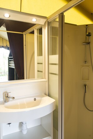 Un baño con lavamanos blanco, un espejo y cabina de ducha de vidrio.