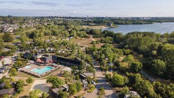 An aerial view of a resort with a swimming pool, multiple buildings, and a river in the background.