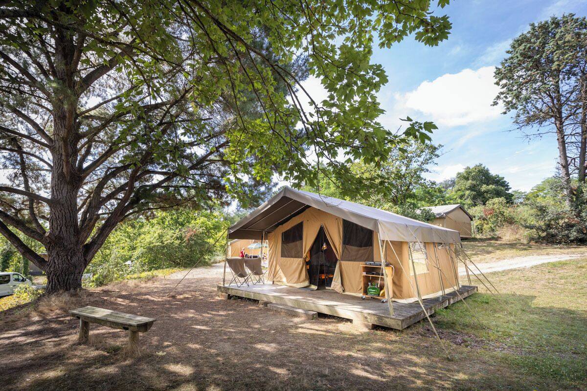 Alojamento em tenda com varanda, um banco e uma mesa.