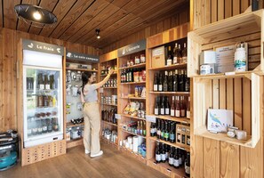 Una persona en una tienda de madera con estantes llenos de botellas de vino y diferentes productos alimenticios.