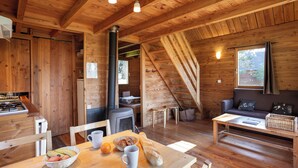 Un interior acogedor de cabaña con una mesa de comedor, sillas, un sofá y una chimenea.