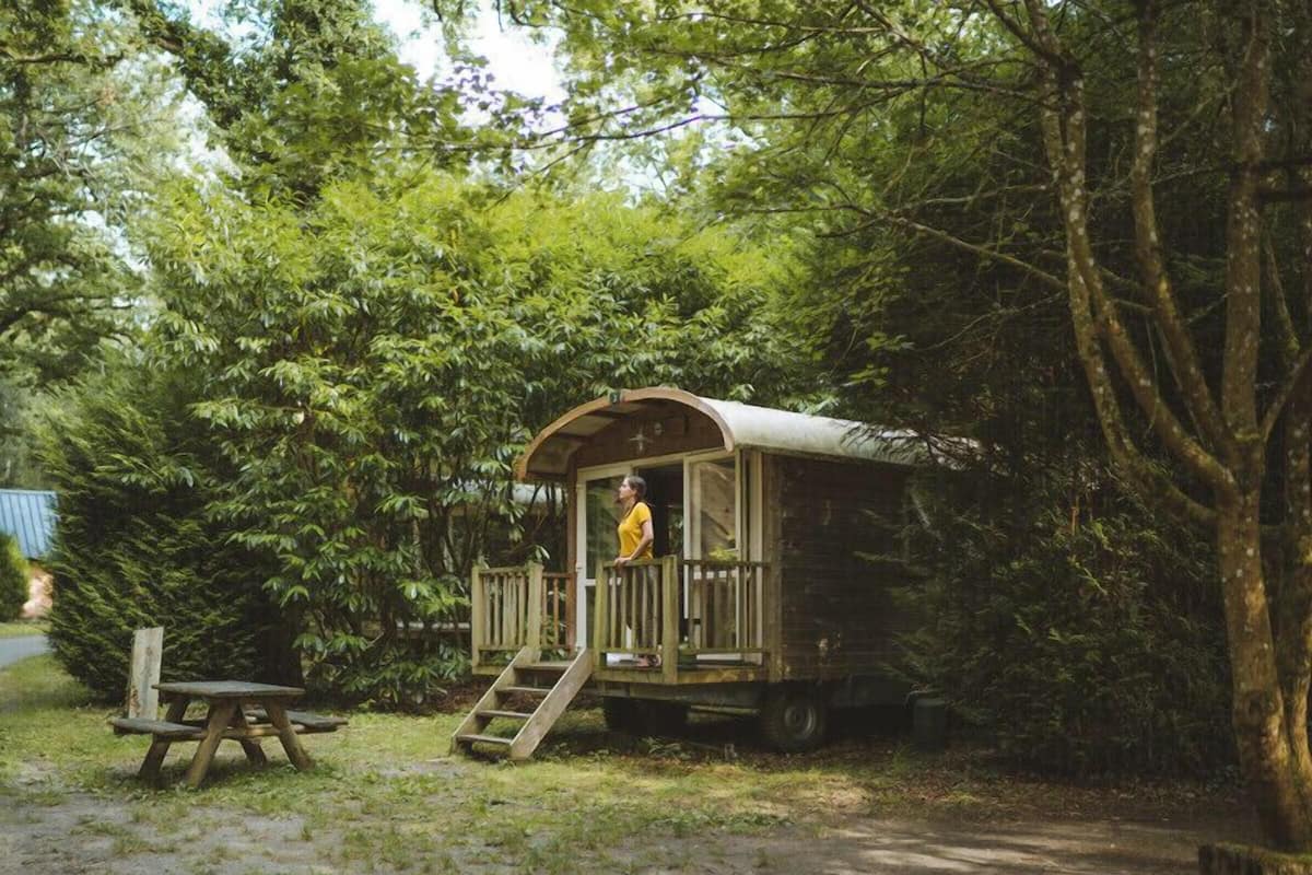 A rustic wooden cabin with a porch and a table nearby.
