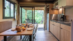 A modern kitchen with wooden cabinets, a stainless steel refrigerator, and a dining area with a table set for breakfast.
