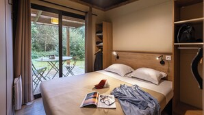 A bedroom with a bed, a table with chairs, and a view of the outdoors.