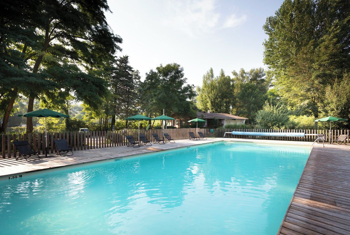 A rectangular swimming pool with a wooden deck and lounge chairs.