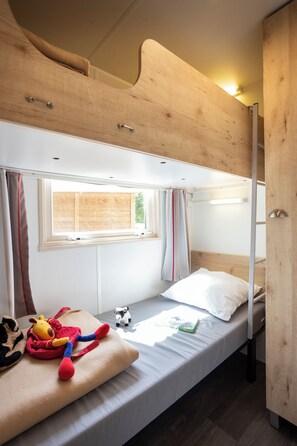 A bunk bed with a window, a small table with a stuffed toy and a book, and a wardrobe. - Huttopia Millau (Millau)