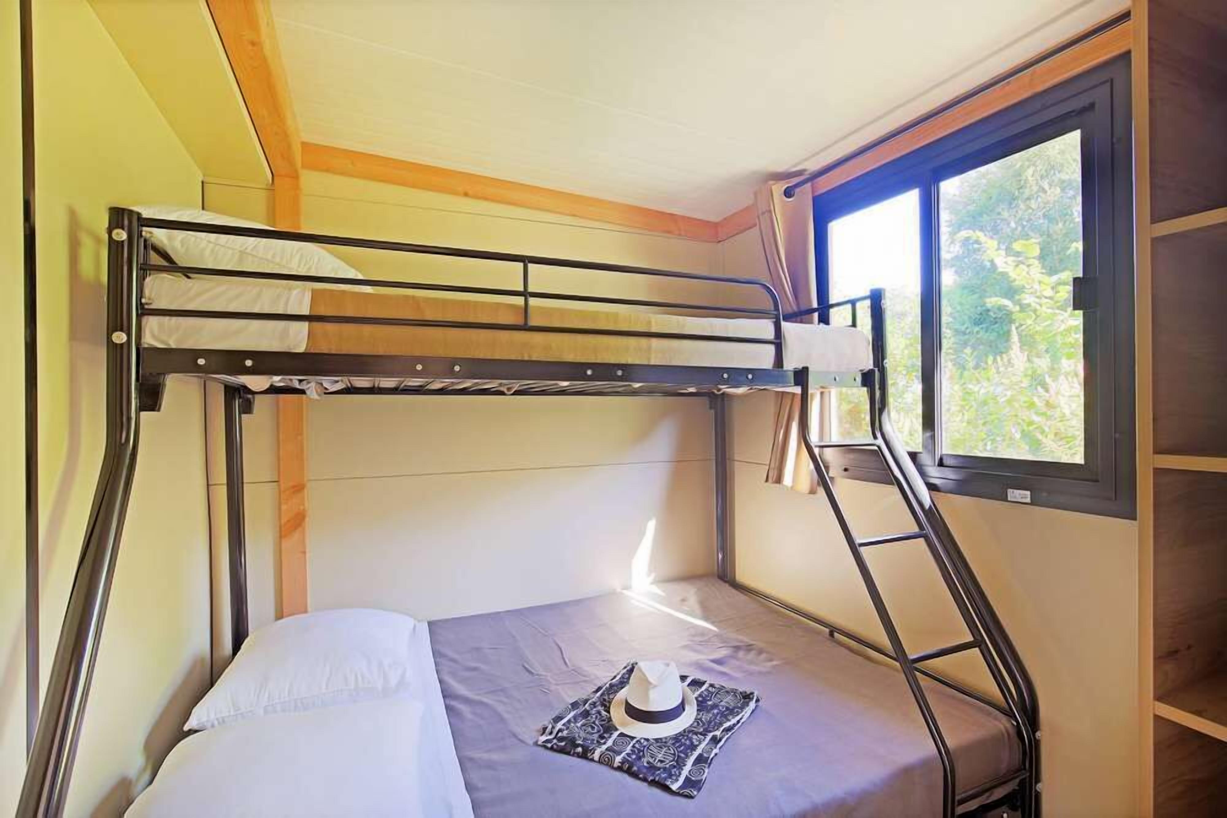 Dormitorio con literas y ventana que ofrece vista a la vegetación.