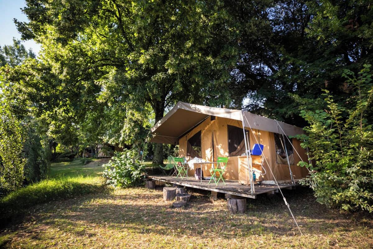 Una cabaña de madera con terraza, rodeada de árboles.